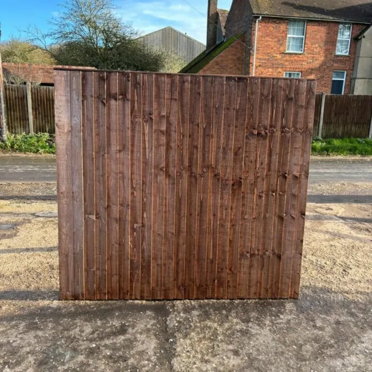 Dark-stained closeboard wooden fence panel displayed upright on a paved surface.