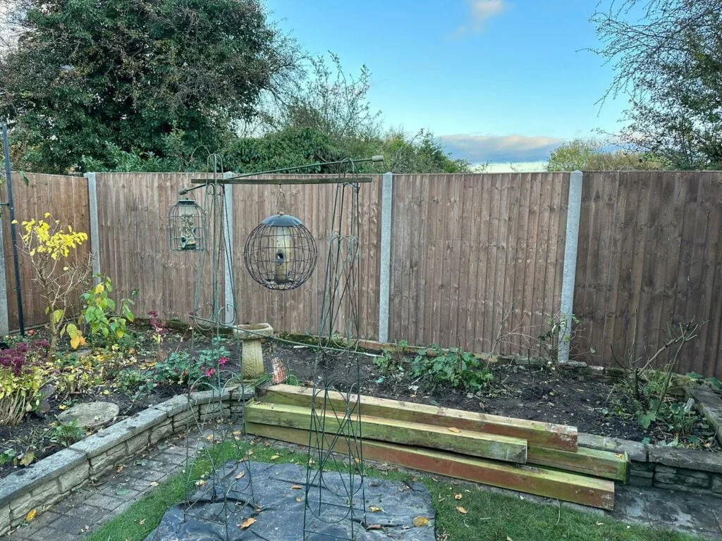Closeboard fence panels with concrete posts installed in a shaded corner garden area.