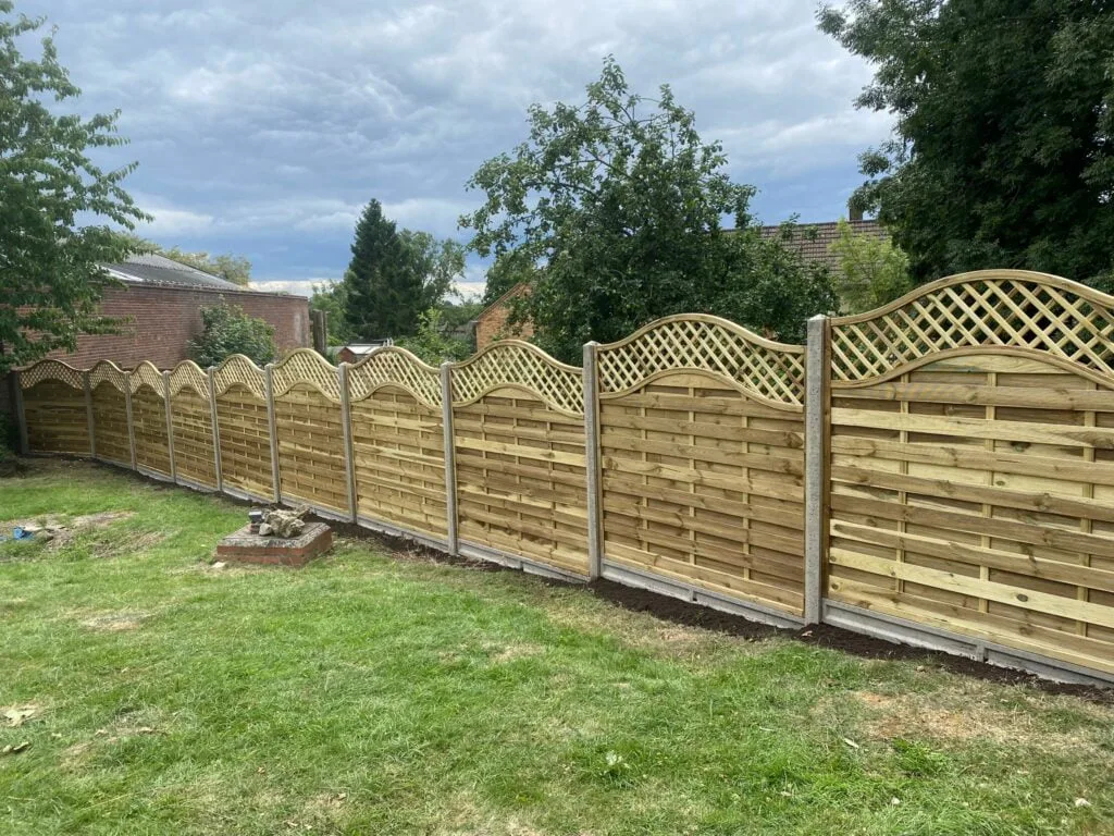 Decorative omega lattice fence panels with curved tops and trellis designs installed in a landscaped garden.